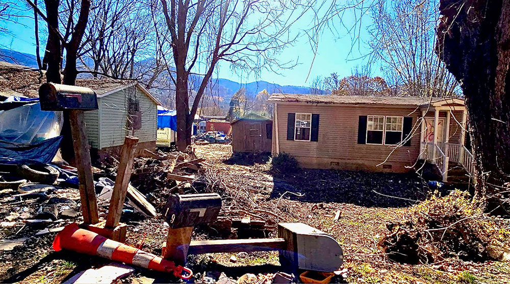 Damaged house with debris in yard.