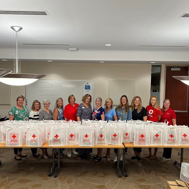 Red Cross volunteers behind table with Red Cross bags.