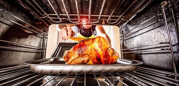 Housewife prepares roast chicken in the oven, view from the inside of the oven. Cooking in the oven. Thanksgiving Day.