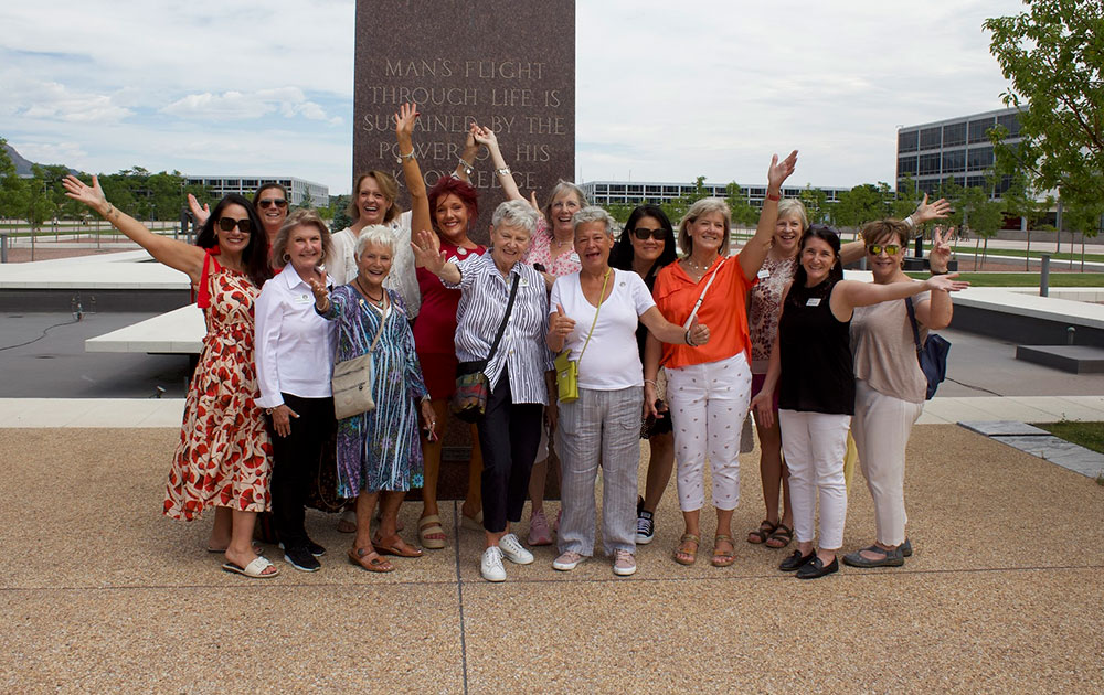 members of the Colorado and Wyoming Tiffany Circle at the U.S. Air Force Academy in Colorado Springs group photo with their hands raised in the air.
