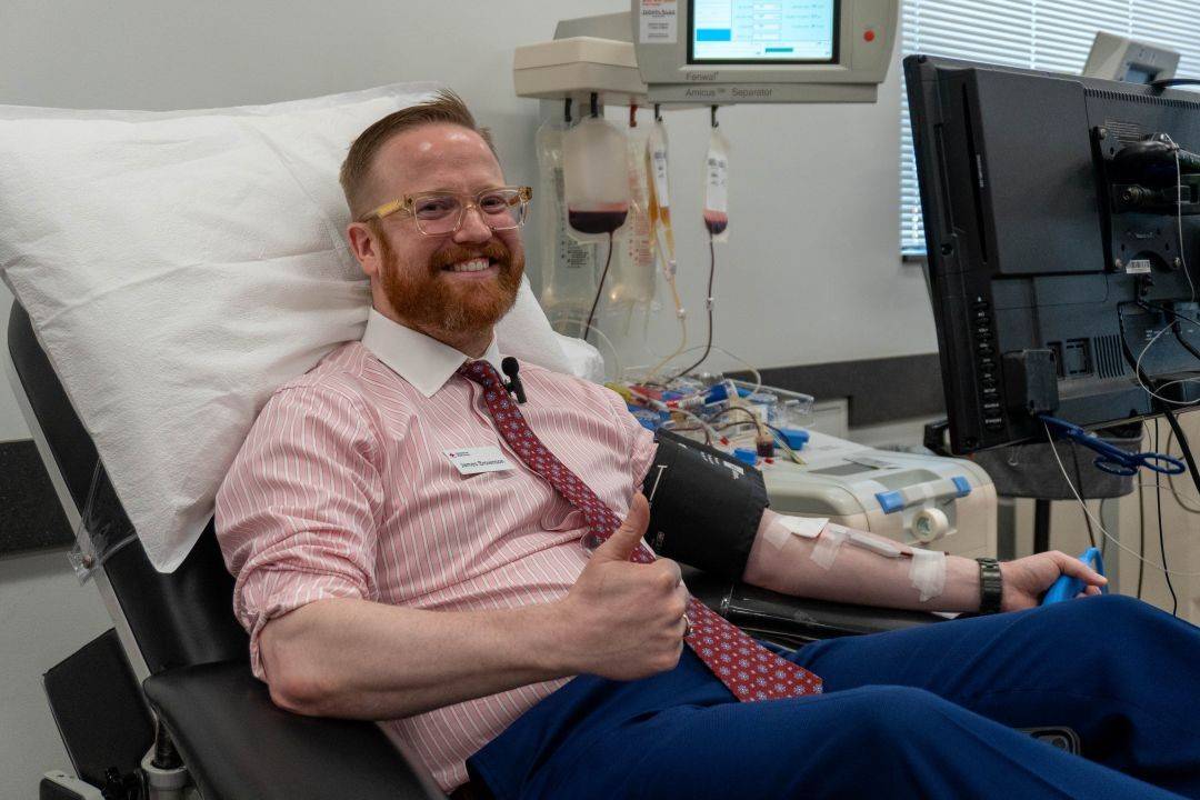 James smiles and gives thumbs up while donating blood