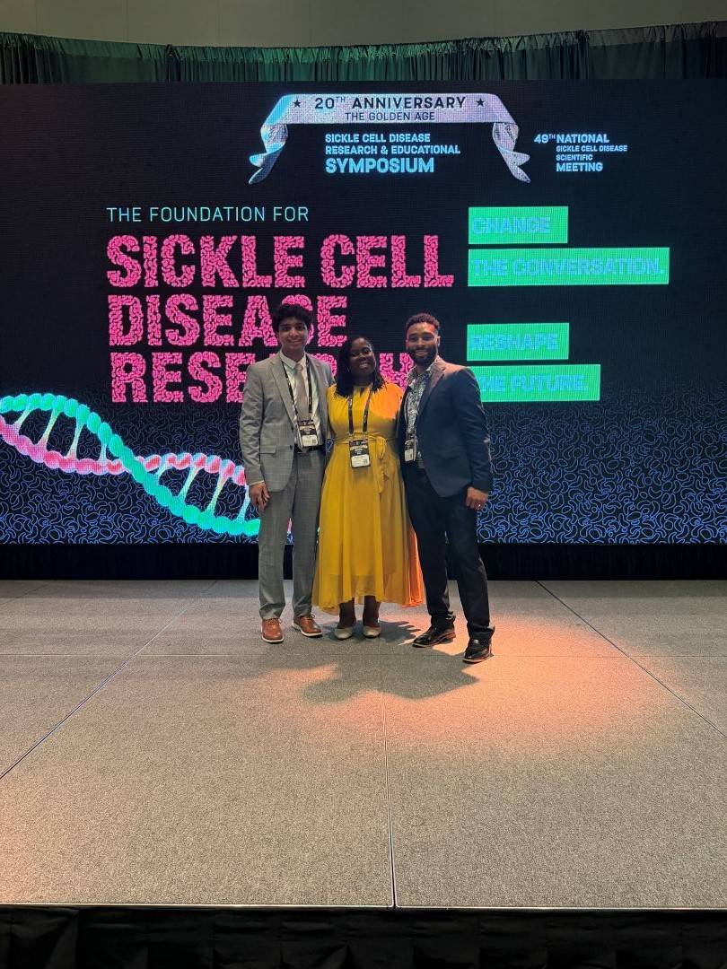 Three people stand on stage at Sickle Cell conference