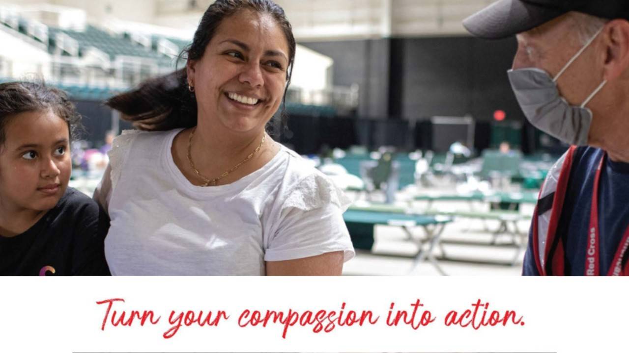 two people in shelter talking to red cross volunteer