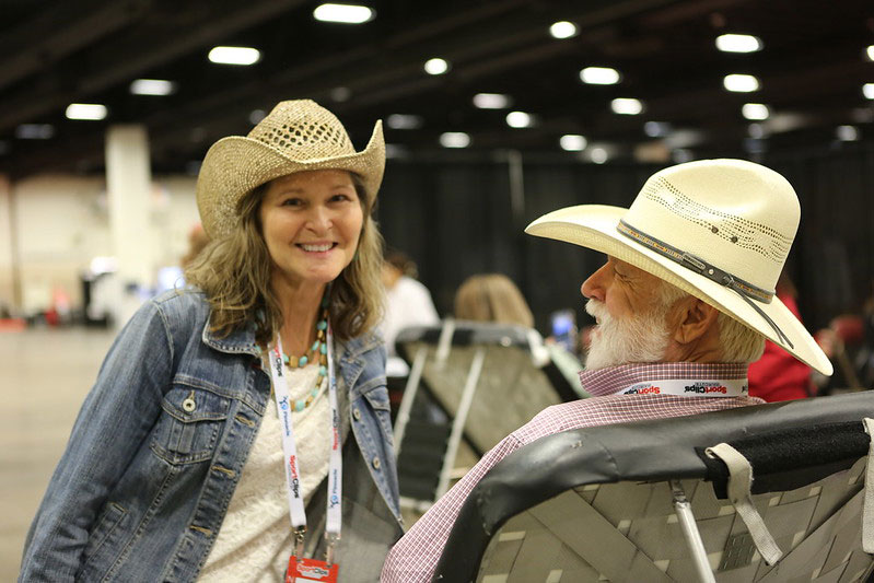 Lady and man with cowboy hats smiling for camera while man waiting to give blood