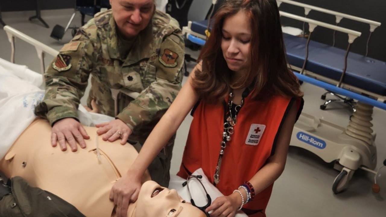 youth volunteer practicing cpr on test dummy