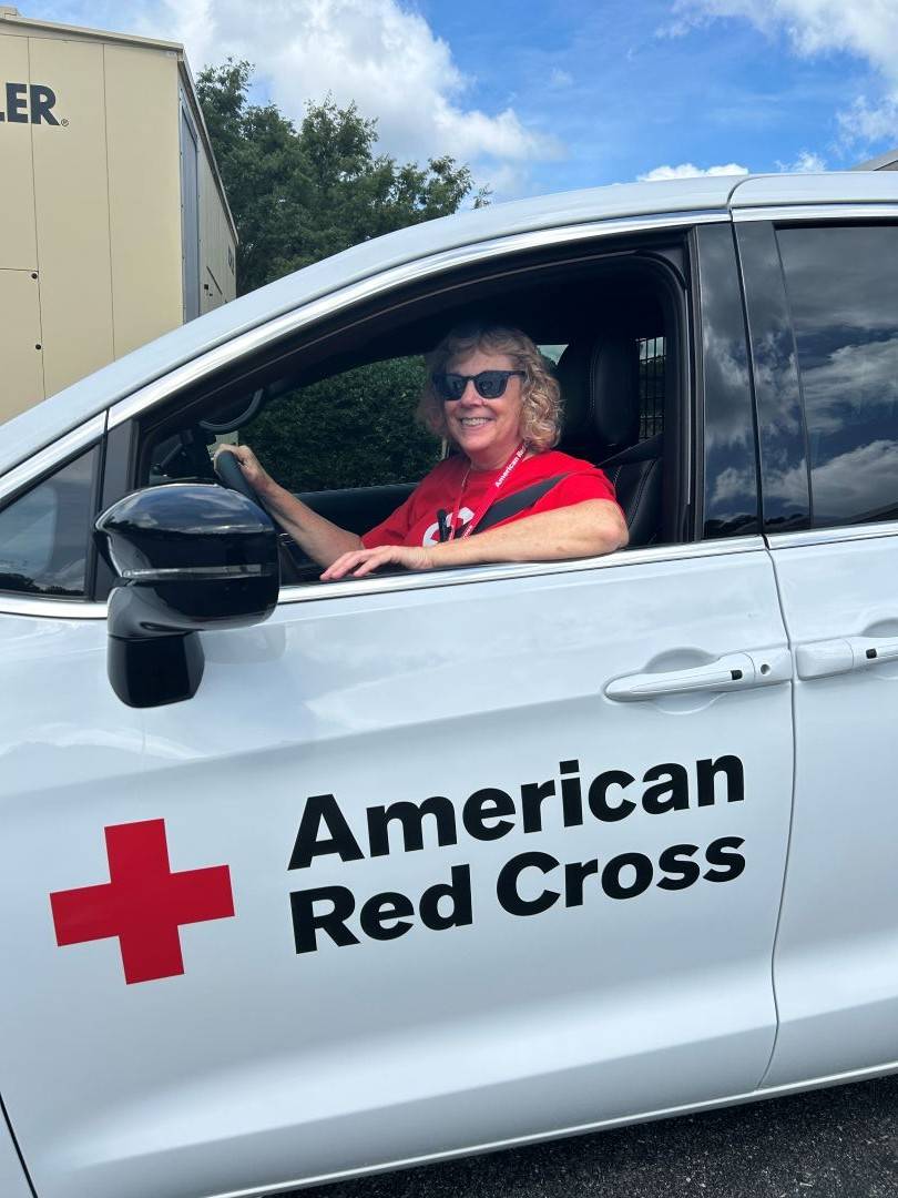 Woman sits in the divers seat of a Red Cross vehicle