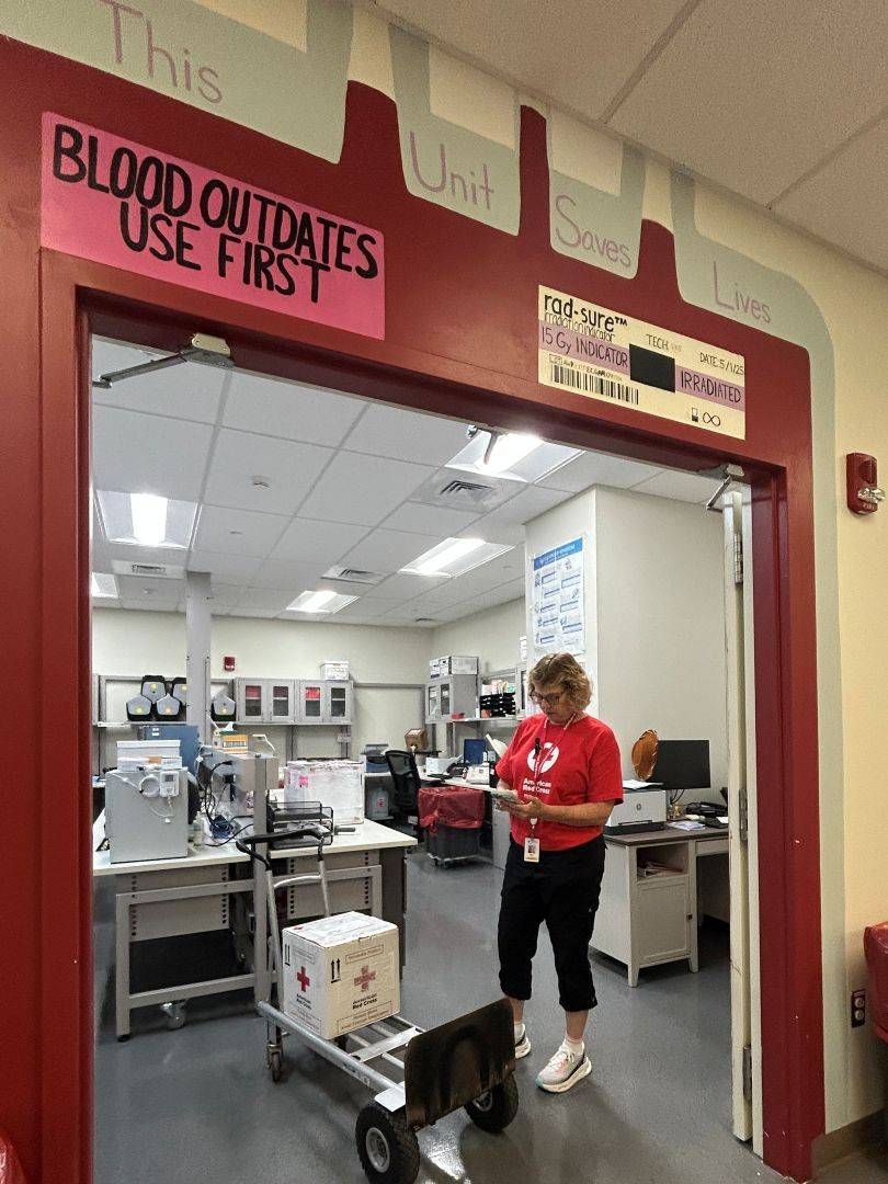 Woman in Red Cross shirt unloads boxes of blood products at a hospital