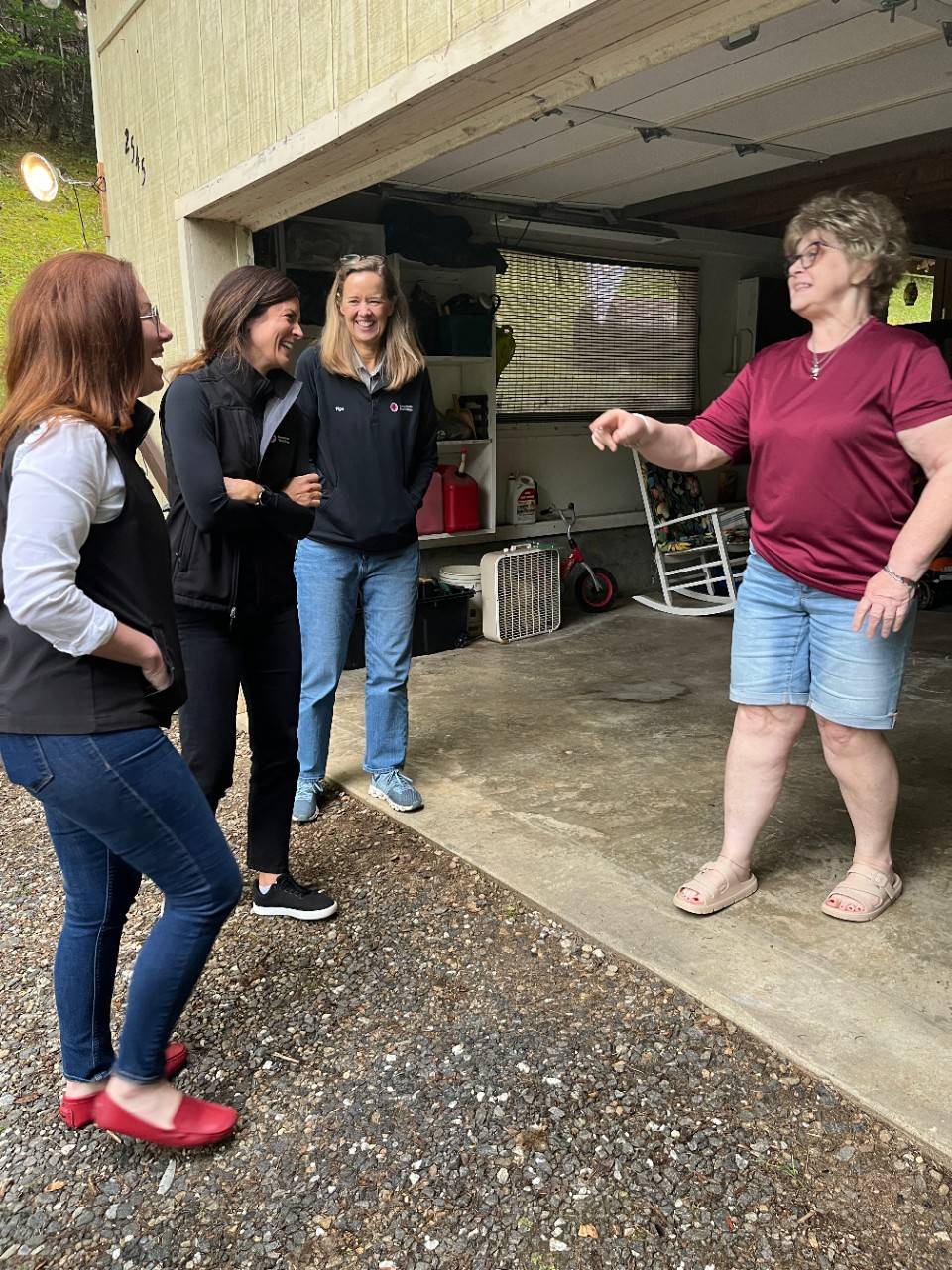 Women stand in garage having conversation and laughing