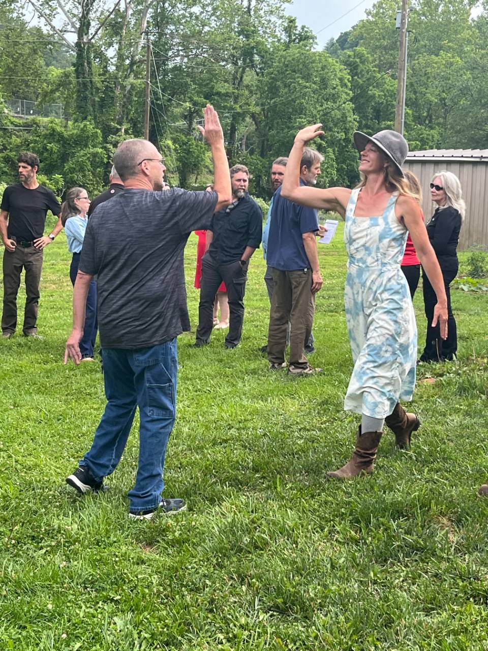 Man high fives woman in outdoor grassy area