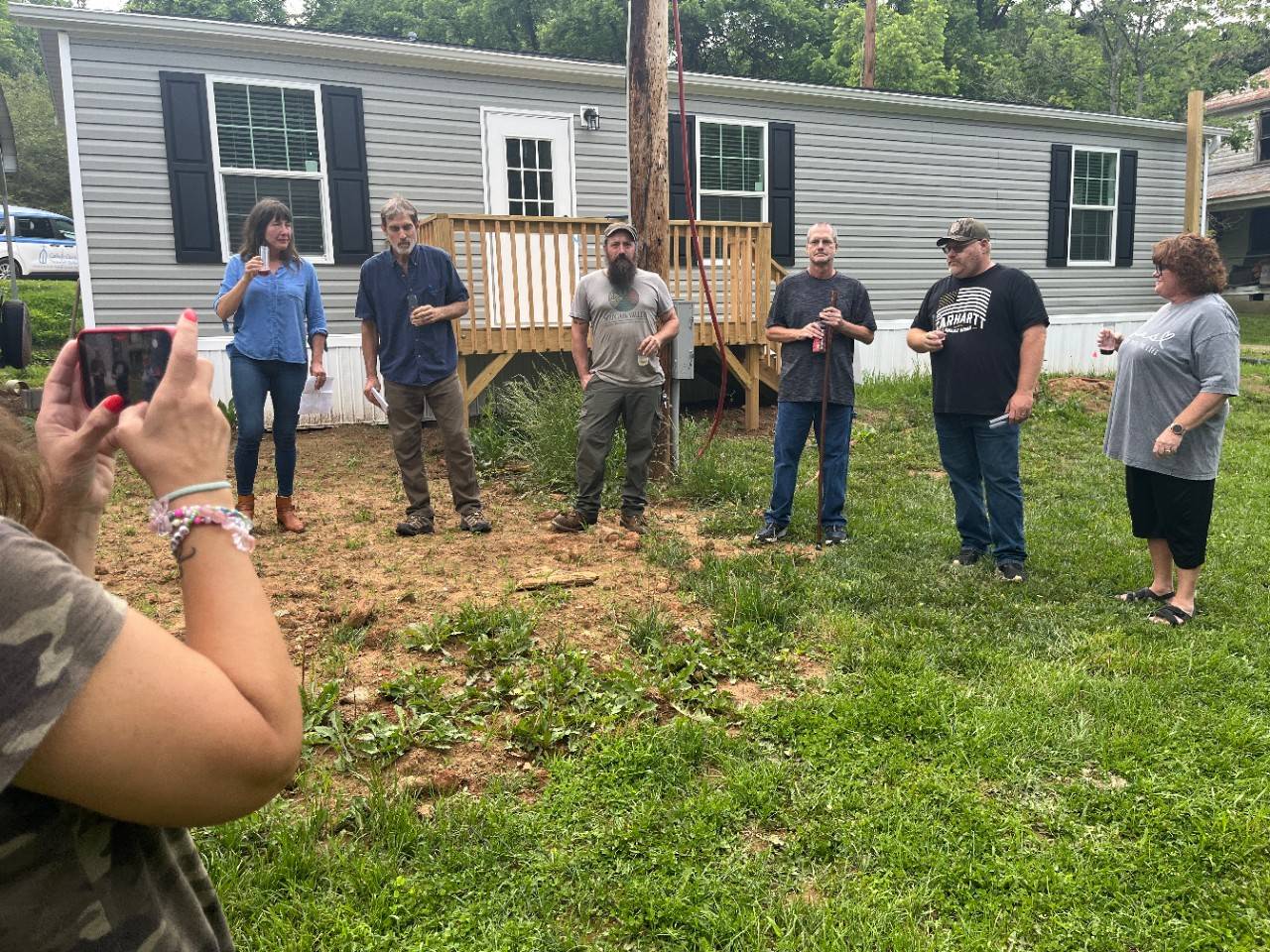 Group of people stand in a line outside of home talking