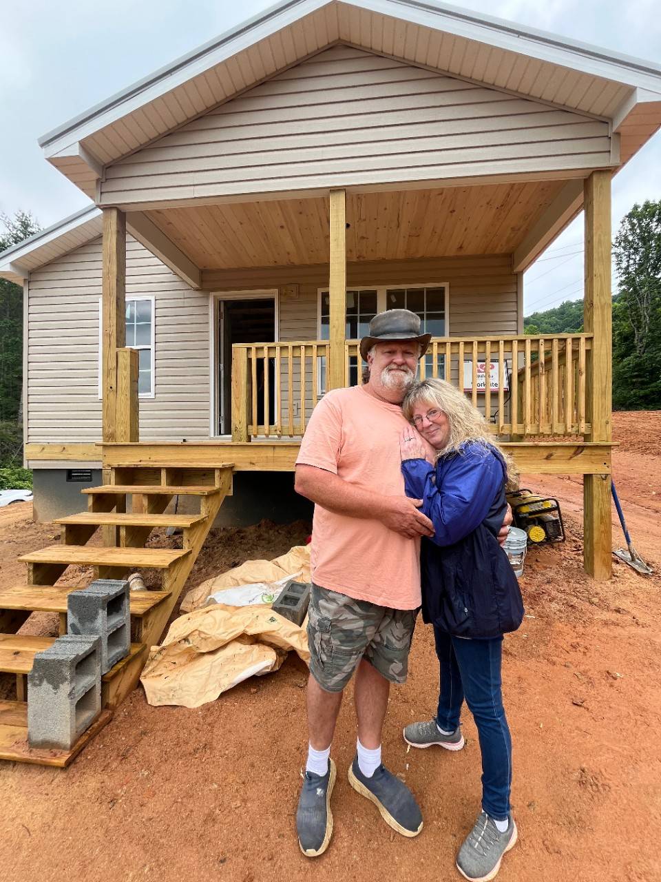 Man and woman embrace outside of home under construction