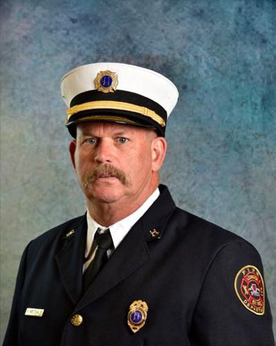 Ronnie Metcalf wearing a fire captian uniform.