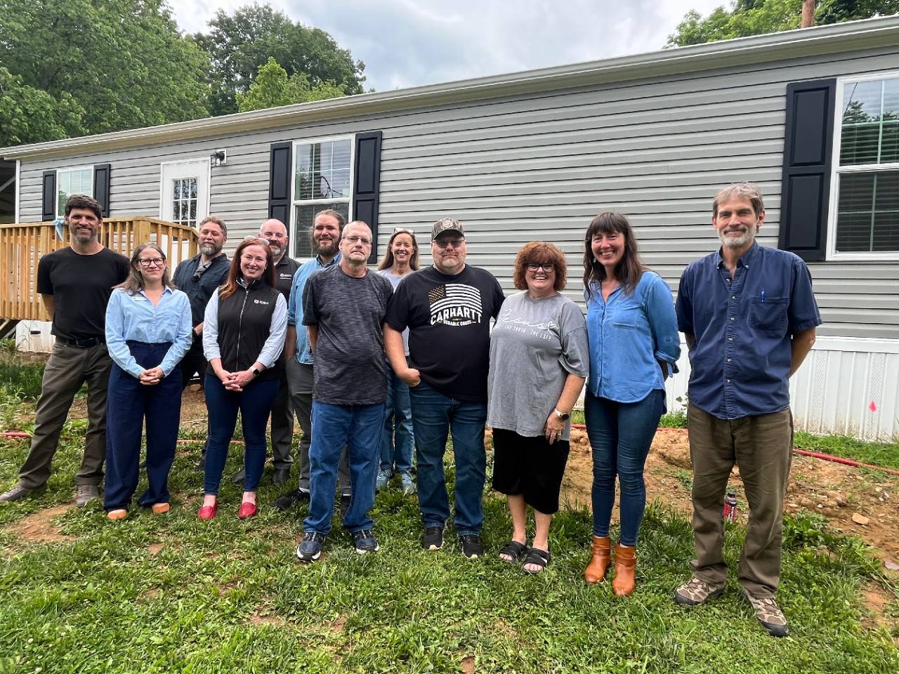 Group of people stand outside newly constructed home