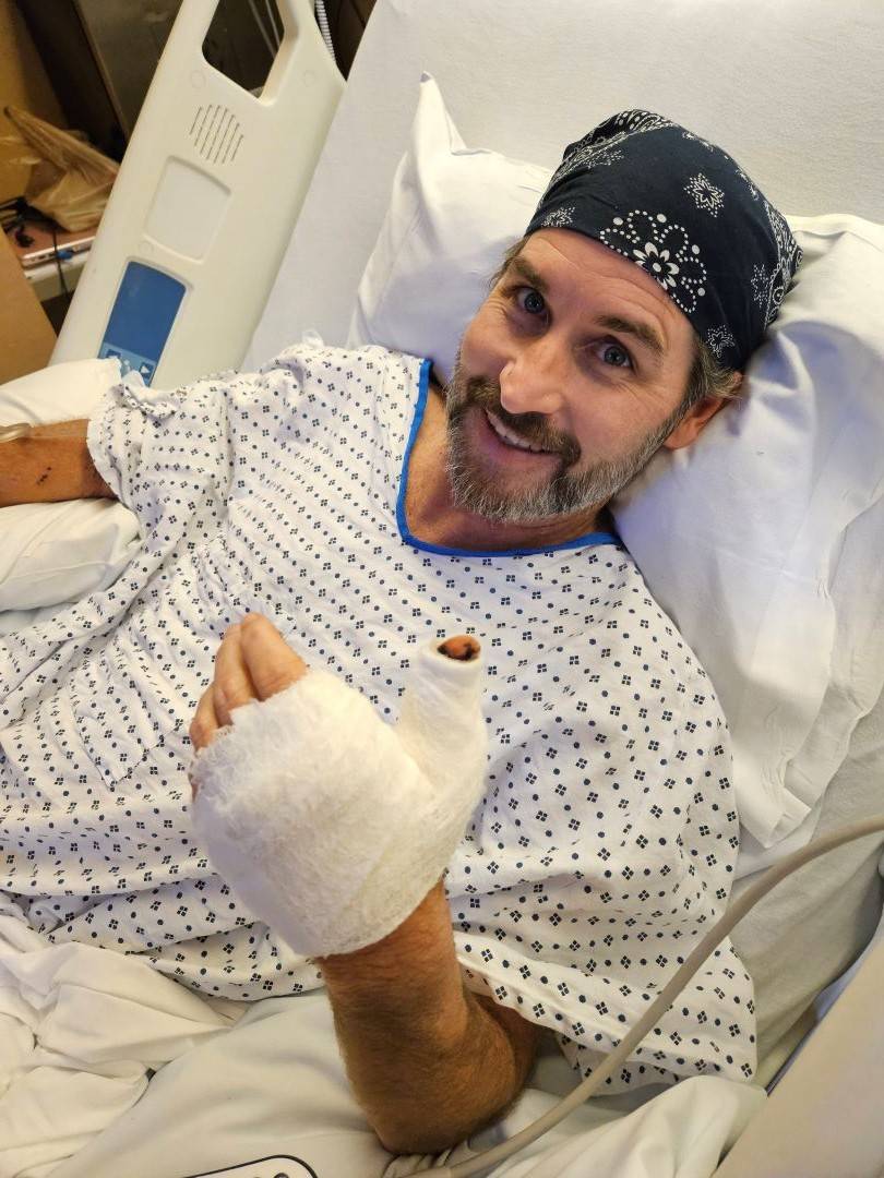 Man gives thumbs up while in hospital bed