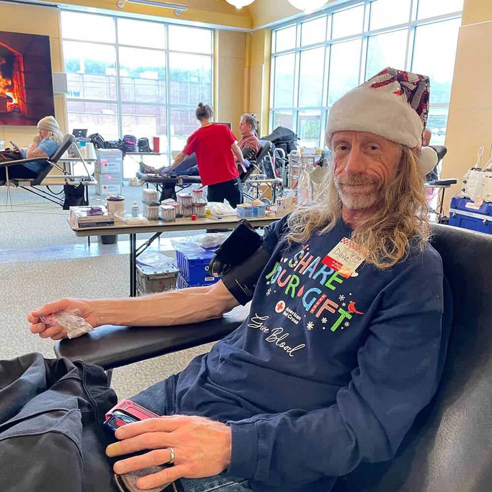 a person wearing a holiday hat, sitting in a chair donating blood.