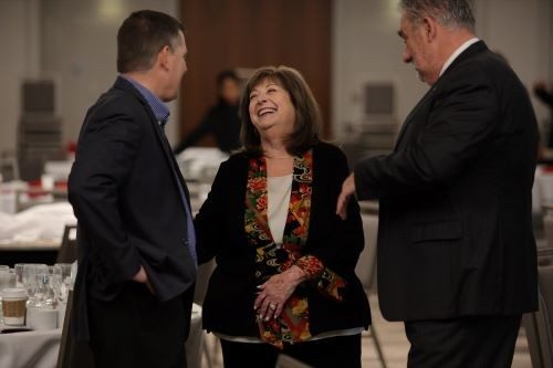 Lorraine Dodero standing and laughing with two men 