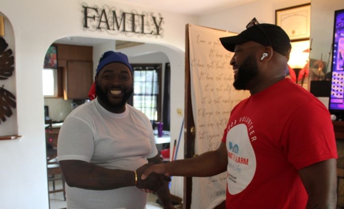 A red cross volunteer shaking a clients hand while smiling 