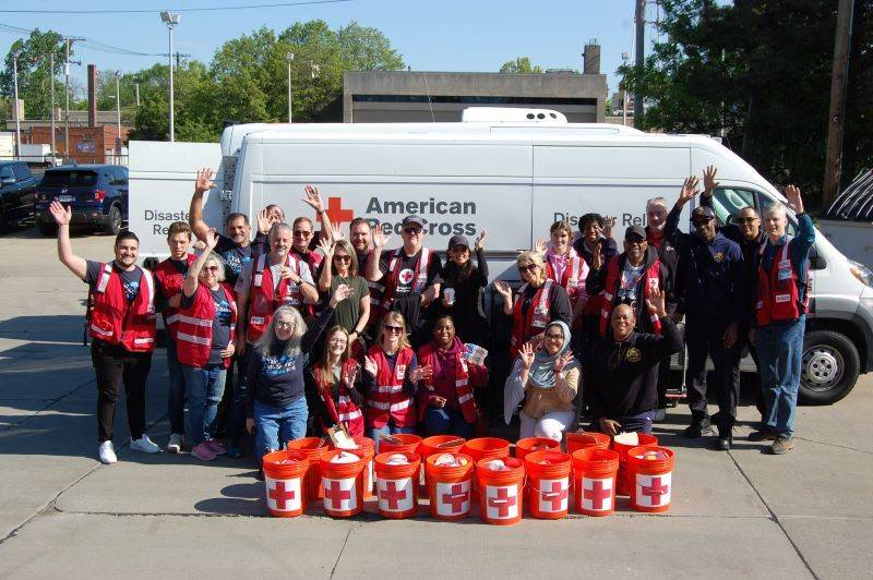 A greoup of Red Cross volunteers standing in front of a Red Cross van.