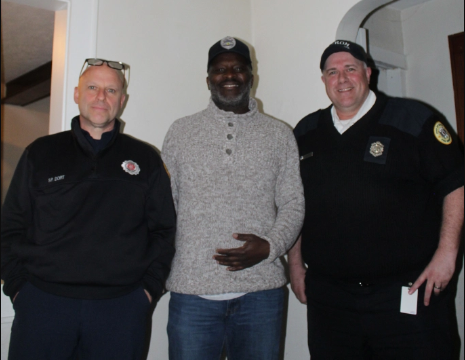 Two red cross volunteers standing with a fire firefighter