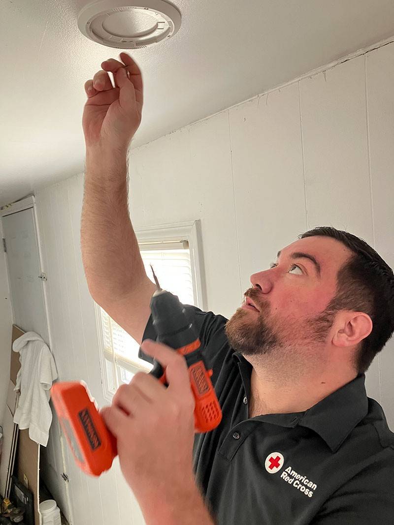 Red Cross volunteer installing smoke alarm