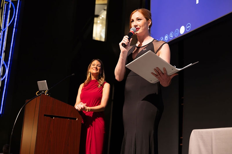 person holding mic and speaking on stage at the heroes award event.
