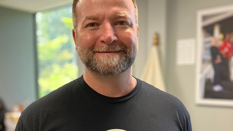 A man smiling and wearing a Red Cross t-shirt.