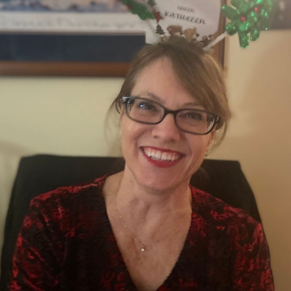 Kathleen Thompson wearing glasses, holiday headband and smiling.