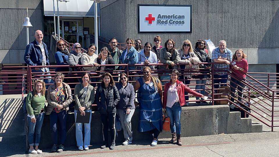 group of Red Cross volunteer nurses in front of a Red Cross building.