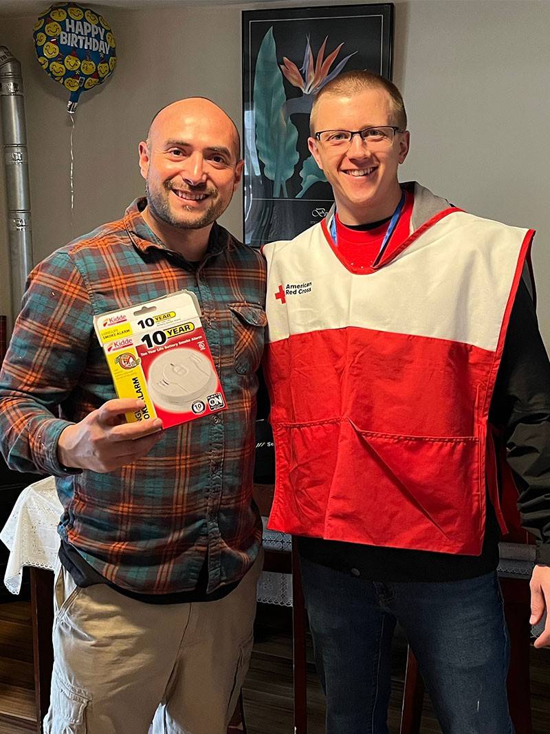 Red Cross volunteer with home owner holding smoke alarm box