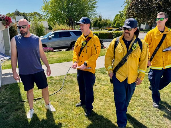 Three firefighters talking to a resident.