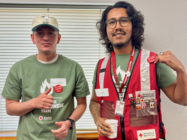 2 Red Cross volunteers in Red Cross vest smiling.
