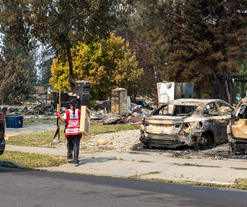 A Red Cross volunteer carrying supplies on a wildfire scene.
