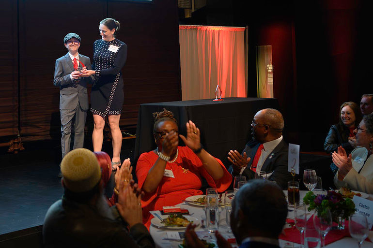 two people on stage in evening attire with one receiving an award at the 27th Annual Red Cross Hero Awards.