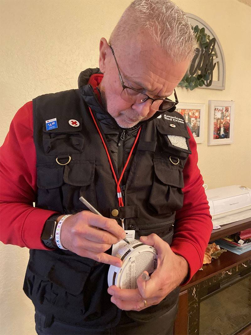 Red Cross volunteer writing on smoke alarm