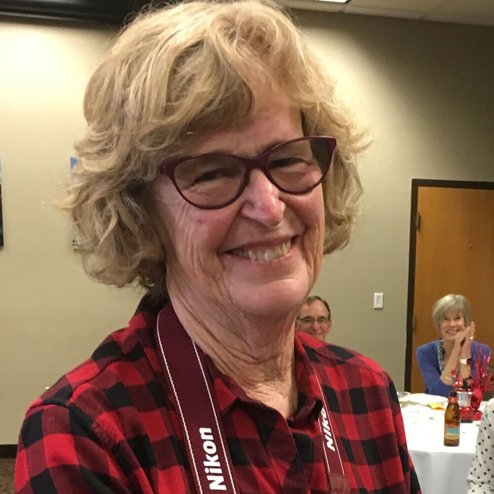 Christina Piaskowski wearing glasses and smiling takes a selfie.