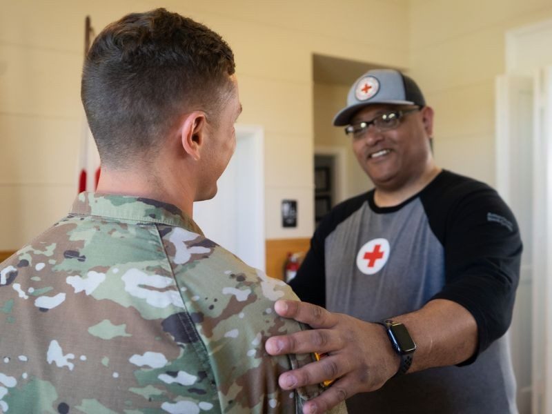 service memeber in uniform hugging red cross volunteer