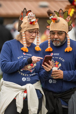 two Run for the Red Turkey Trot participants looking at a smartphone.