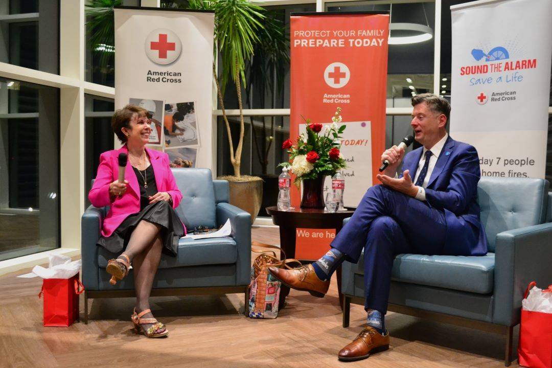 Man and woman have discussion over microphones while sitting in chairs