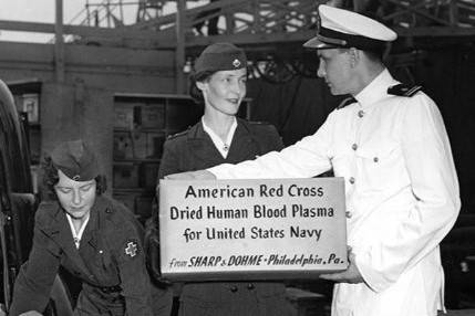 Image from World War II. Red Cross workers hand box of donated blood products to man in military uniform 