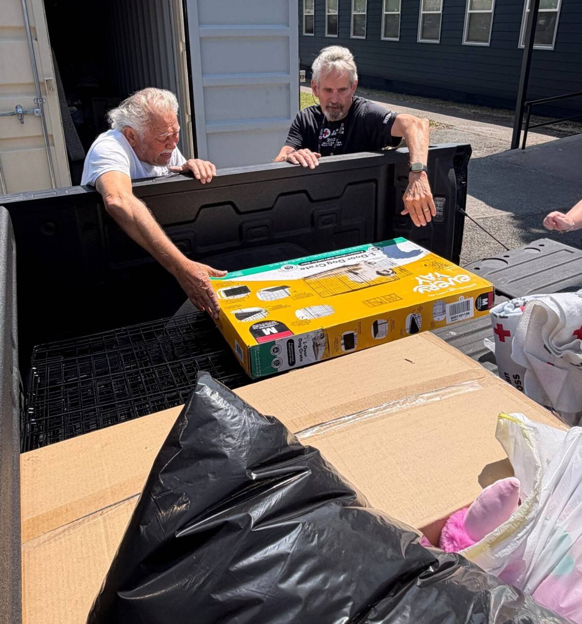 Two men unload supplies from truck