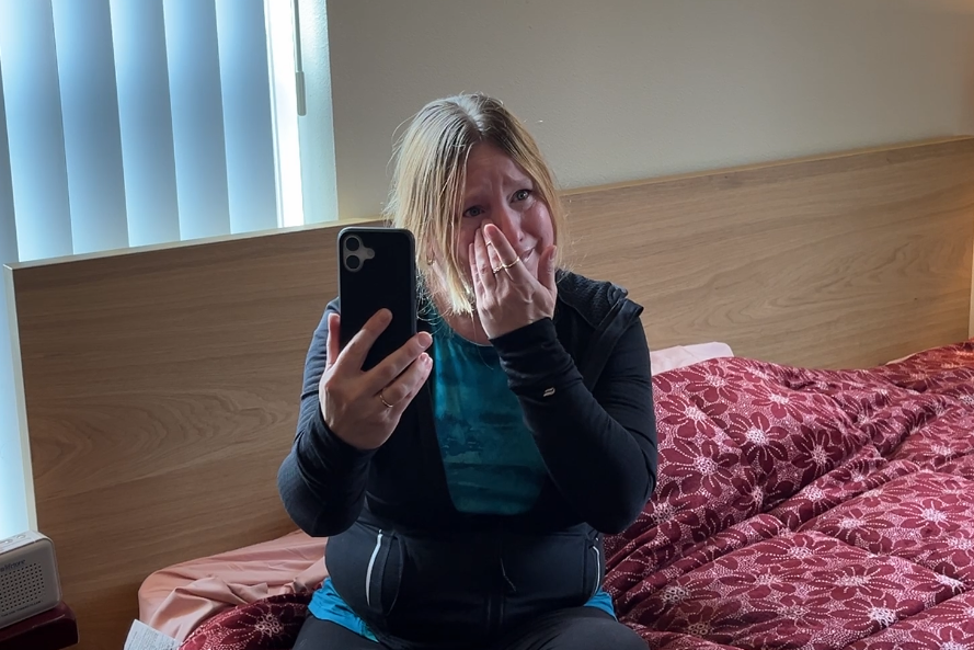 woman cries while sitting on bed with new bed shaker alarm