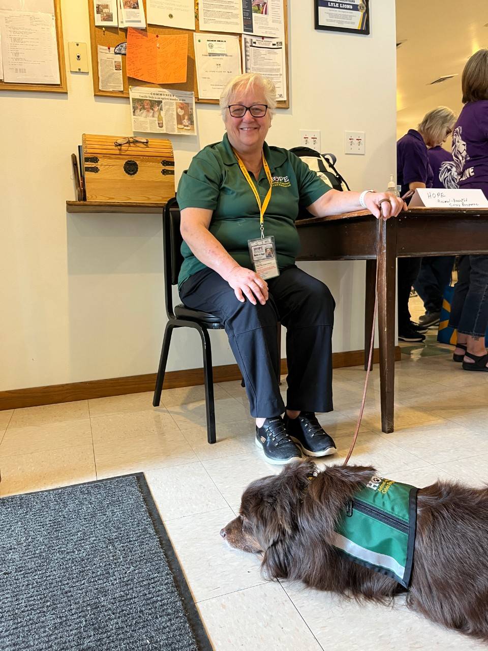 Beckie Miller sitting in a chair with a dog laying on the floor next to her.