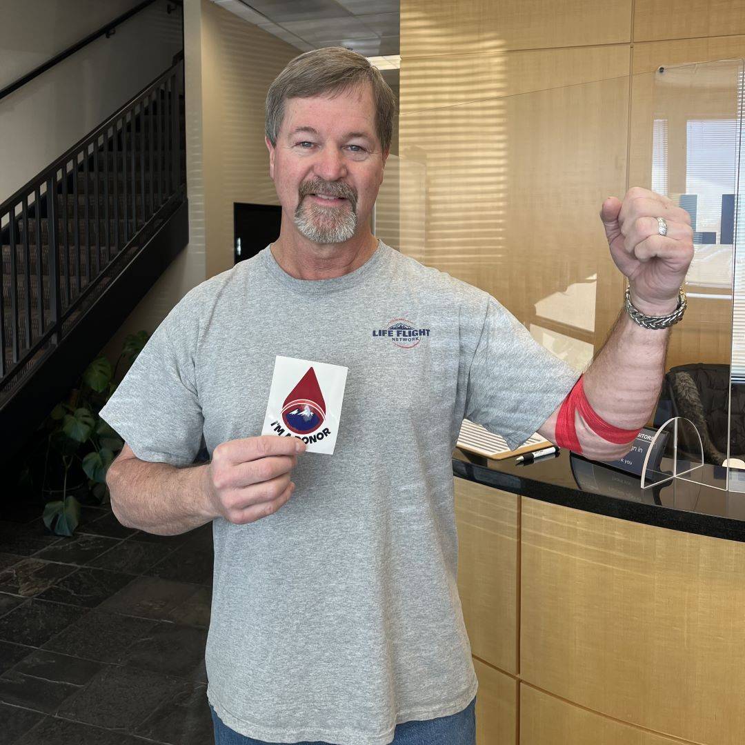 Man holds up arm with bandage after donating blood