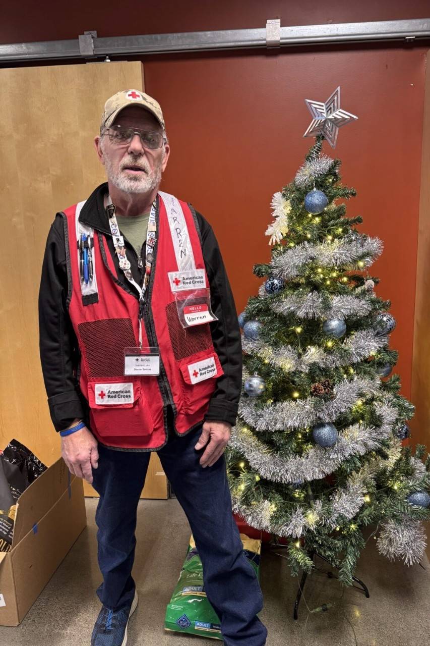 Red Cross volunteer stands in shelter decorated for Christmas