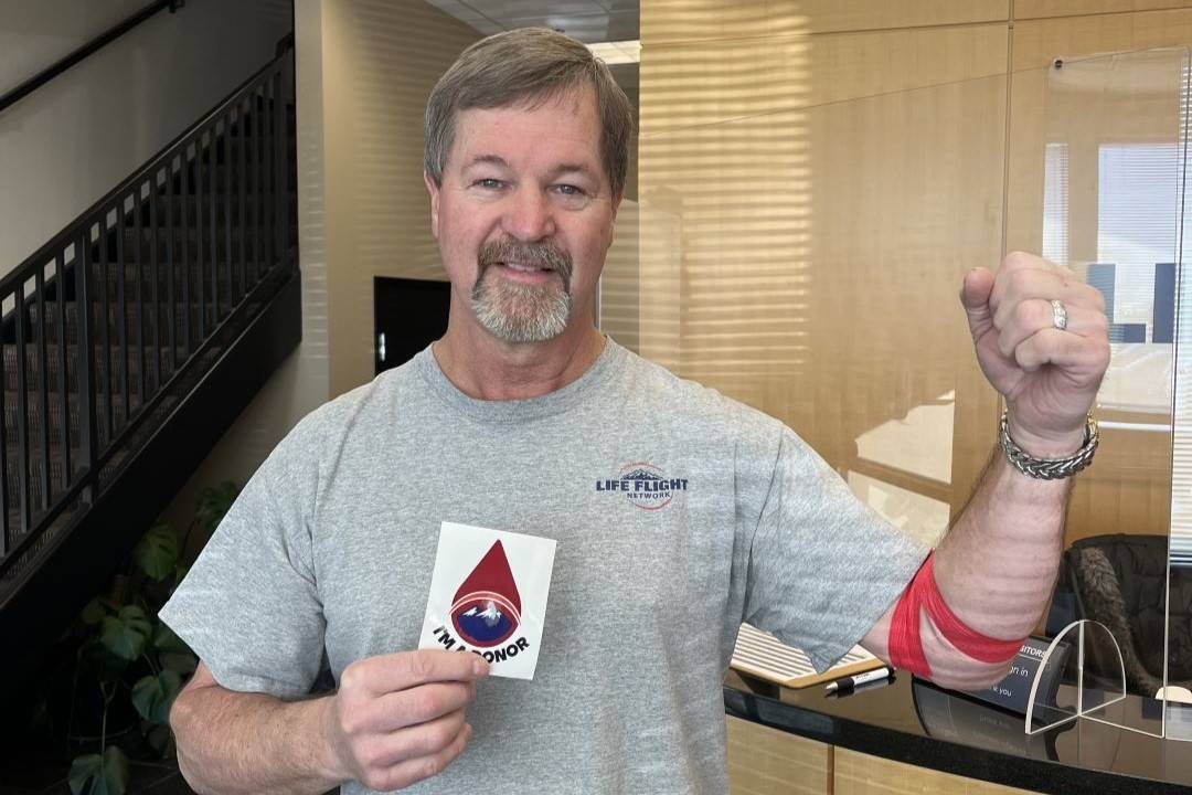 Man holds up bandaged arm after donating blood