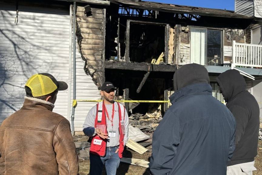 Red Cross volunteer talks to residents outside burned home