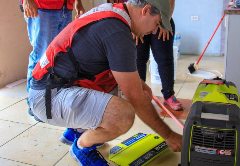 Fotografía de voluntarios de la Cruz Roja entregando un generador eléctrico.