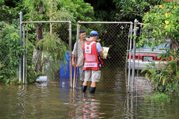 Voluntario de la Cruz Roja asiste a señor afectado por una inundación.