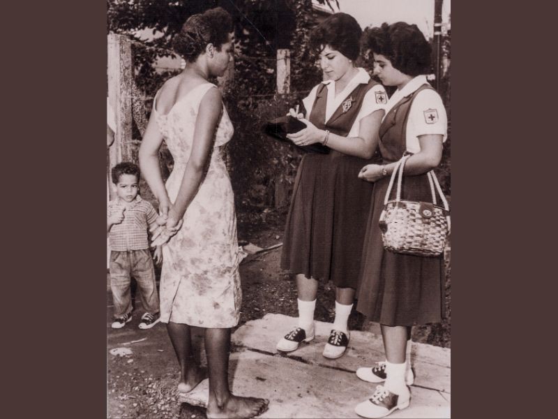 Voluntarias de un consejo juvenil conversan con una señora y toman notas.