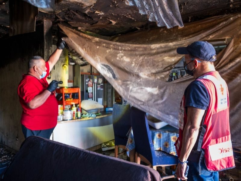Dos voluntarios de ayuda en desastres revisando los daños en viviendas causados por un incendio.